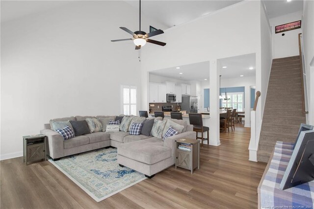 living room with high vaulted ceiling, ceiling fan, plenty of natural light, and wood-type flooring