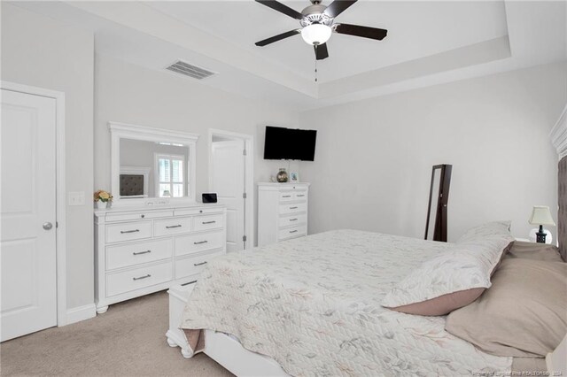 carpeted bedroom featuring a tray ceiling and ceiling fan