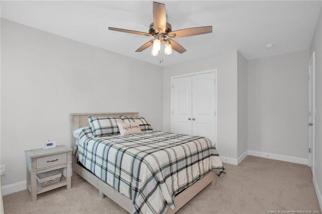 bedroom with light carpet, ceiling fan, and a closet