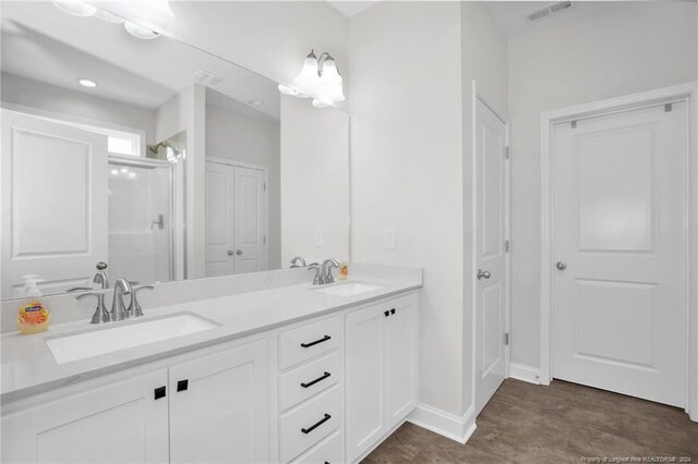 bathroom featuring a shower with shower door and vanity