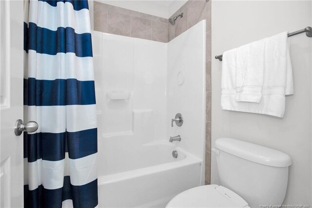 bathroom featuring toilet and shower / tub combo with curtain