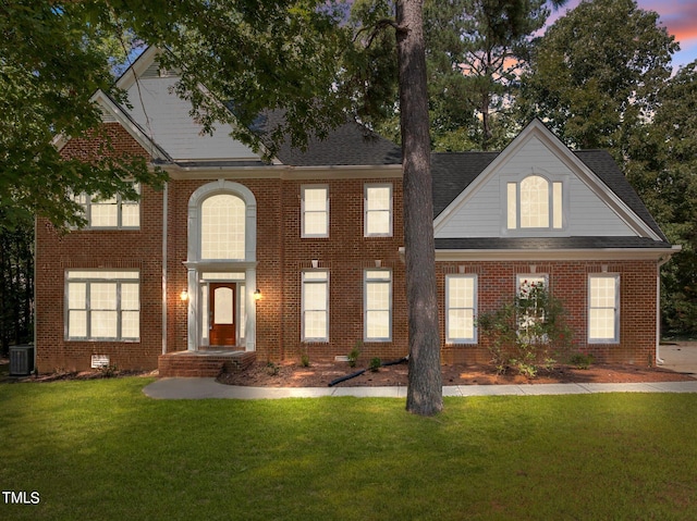 view of front of house featuring central air condition unit and a lawn