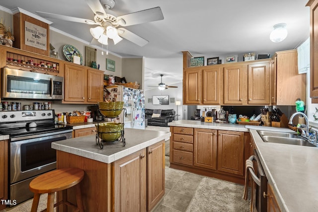 kitchen featuring a kitchen island, appliances with stainless steel finishes, ornamental molding, sink, and ceiling fan