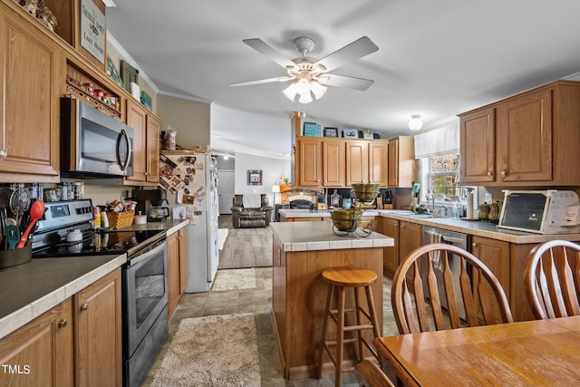 kitchen featuring stainless steel appliances, a kitchen island, ceiling fan, vaulted ceiling, and a breakfast bar area