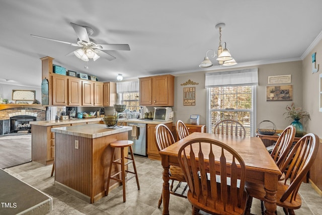 dining space featuring a stone fireplace, ornamental molding, and ceiling fan with notable chandelier