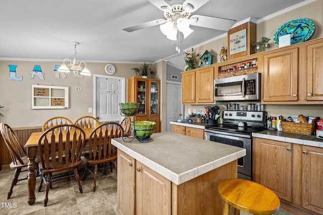 kitchen featuring vaulted ceiling, ceiling fan with notable chandelier, a center island, stainless steel appliances, and ornamental molding