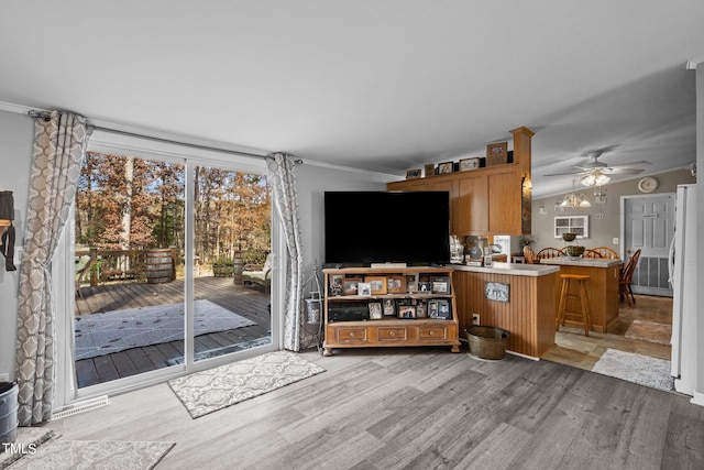 kitchen with light hardwood / wood-style flooring, a kitchen breakfast bar, kitchen peninsula, ceiling fan, and white refrigerator