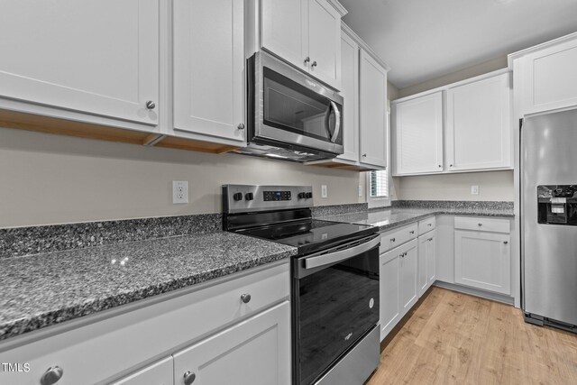 kitchen with dark stone counters, light hardwood / wood-style flooring, white cabinets, and stainless steel appliances