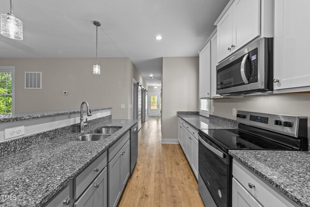 kitchen with white cabinets, sink, dark stone countertops, light hardwood / wood-style floors, and stainless steel appliances