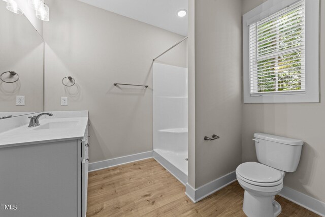 bathroom with hardwood / wood-style floors, vanity, toilet, and a shower