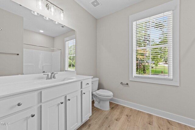 bathroom featuring hardwood / wood-style flooring, vanity, toilet, and walk in shower