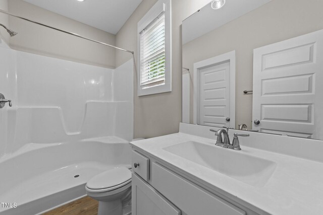 bathroom featuring hardwood / wood-style flooring, vanity, toilet, and walk in shower