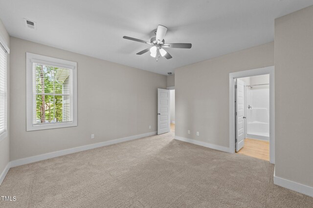 unfurnished bedroom with ceiling fan, light carpet, and ensuite bath