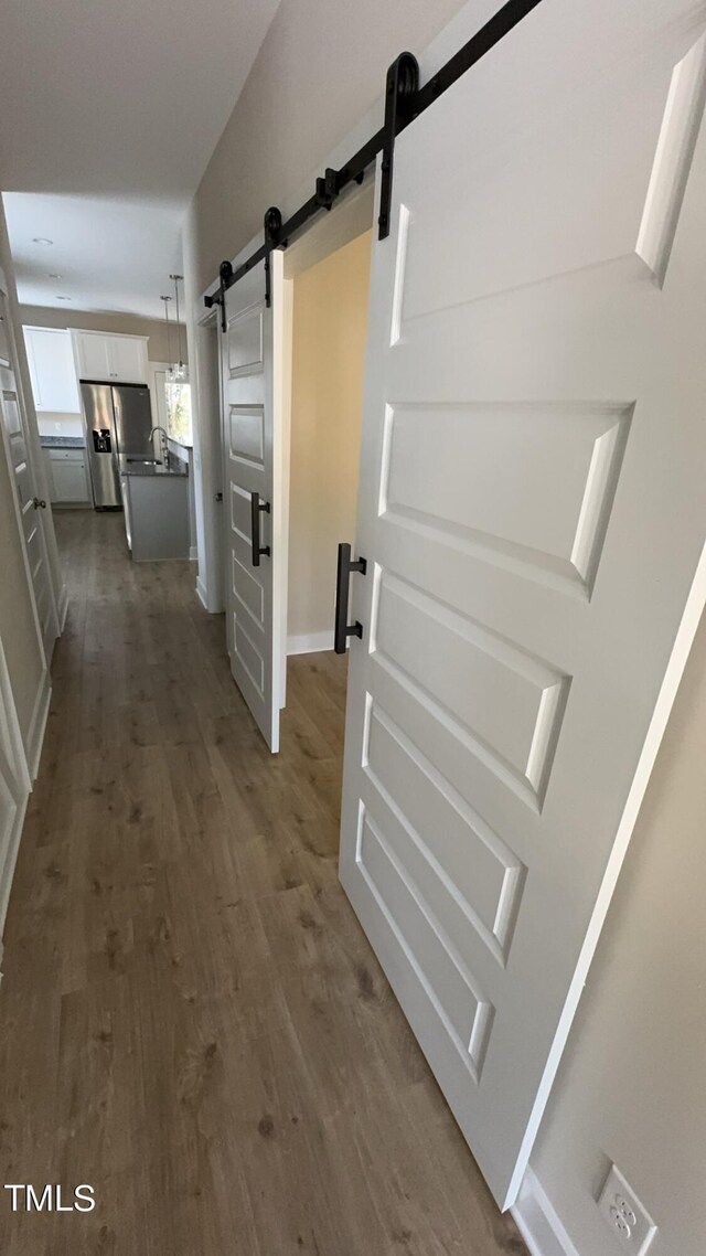 hall with a barn door, sink, and dark wood-type flooring