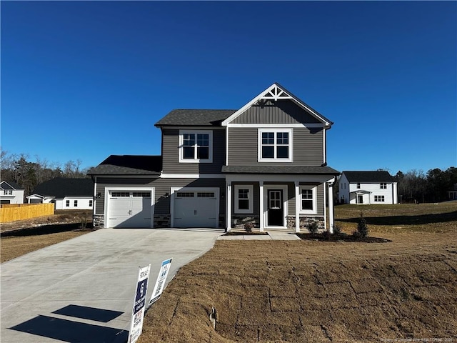 view of front of property featuring covered porch, a front yard, and a garage