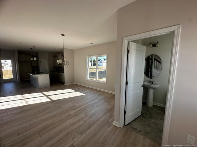 unfurnished living room with dark hardwood / wood-style floors, an inviting chandelier, and sink