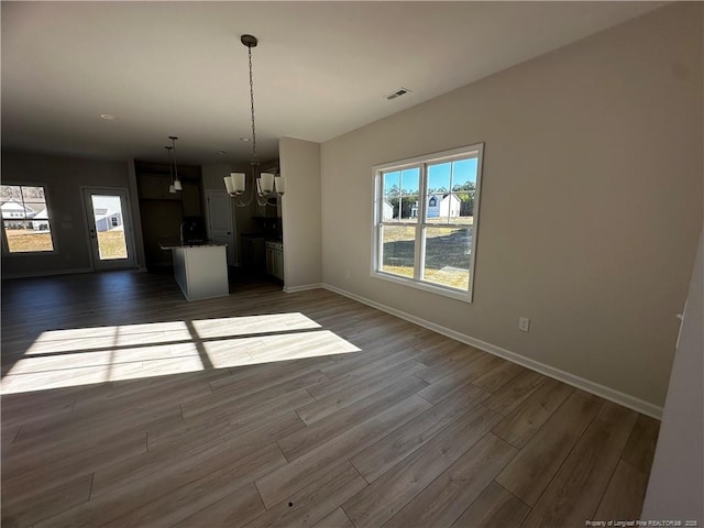 unfurnished dining area featuring dark hardwood / wood-style flooring and a notable chandelier