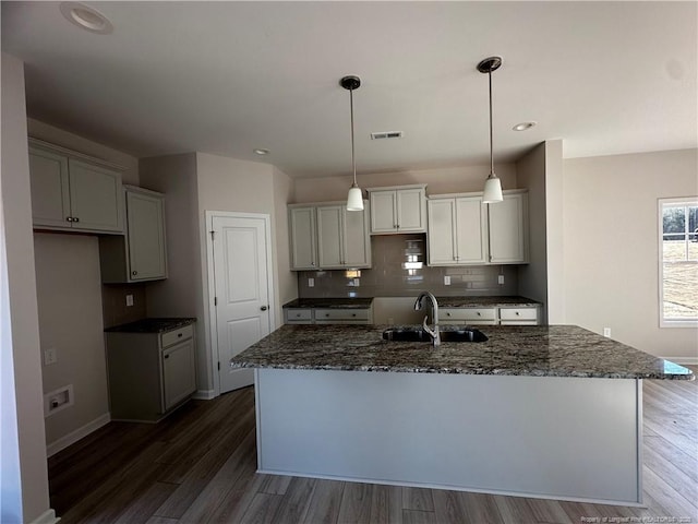 kitchen featuring a center island with sink, dark wood-type flooring, sink, and tasteful backsplash