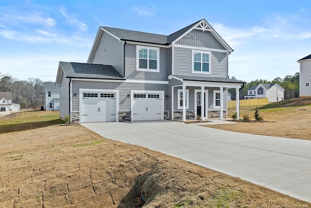 craftsman-style house featuring covered porch, stone siding, board and batten siding, and driveway