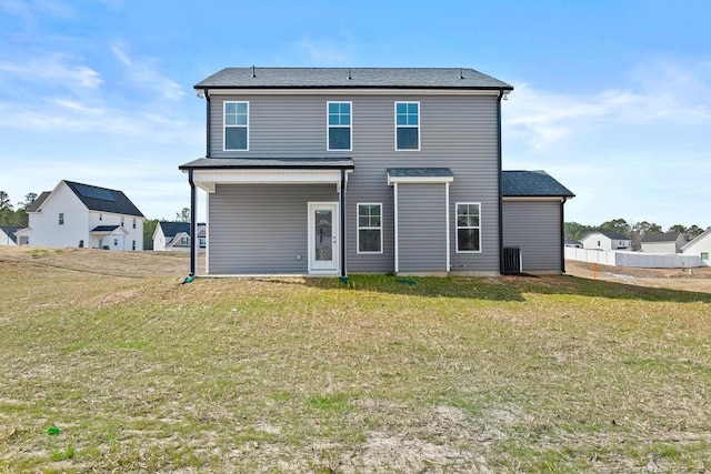 back of property with a lawn and fence