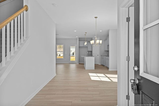 foyer with recessed lighting, baseboards, a notable chandelier, and light wood finished floors