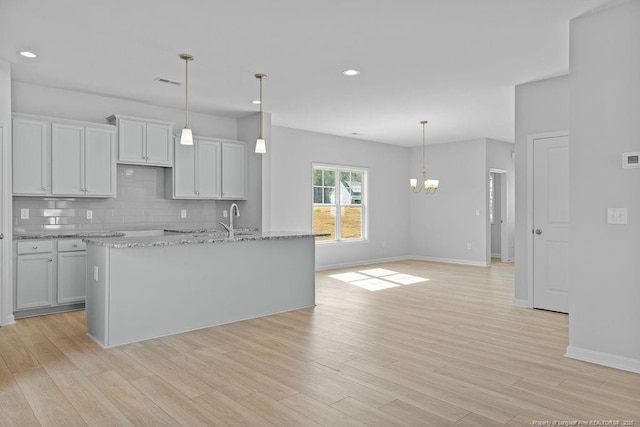 kitchen with light wood-style floors, decorative light fixtures, a notable chandelier, and decorative backsplash