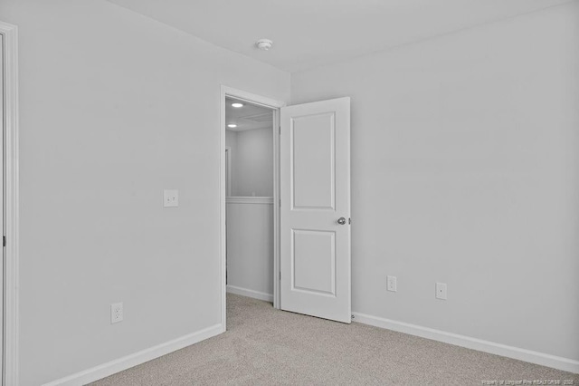 unfurnished room featuring light carpet and baseboards