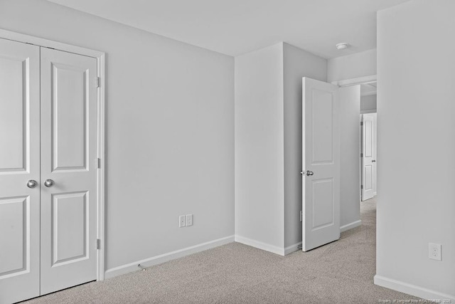 unfurnished bedroom with light colored carpet and baseboards