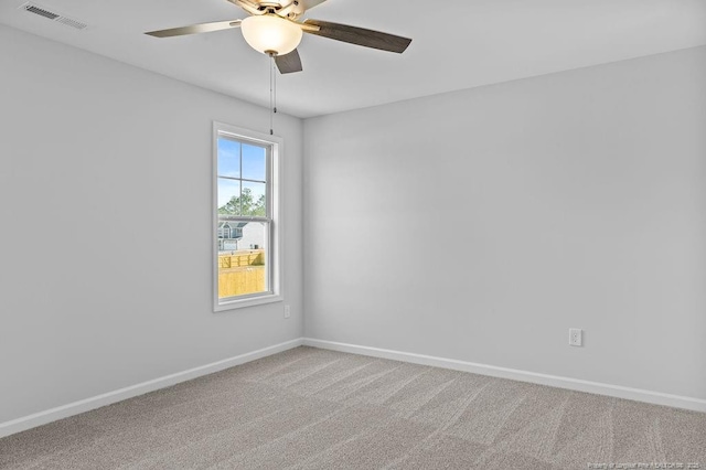 carpeted spare room with a ceiling fan, visible vents, and baseboards