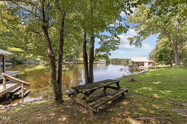 dock area with a lawn and a water view