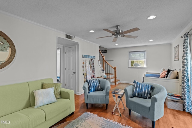 living room featuring wood-type flooring, a textured ceiling, crown molding, and ceiling fan