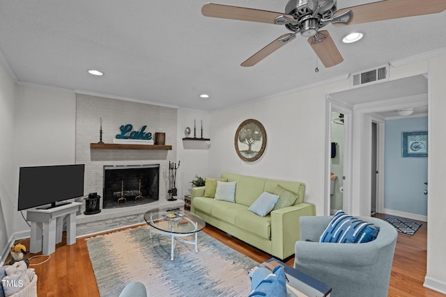 living room with ceiling fan, hardwood / wood-style flooring, a fireplace, and ornamental molding