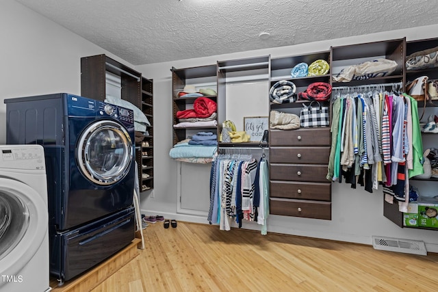 washroom featuring hardwood / wood-style floors, washing machine and clothes dryer, and a textured ceiling