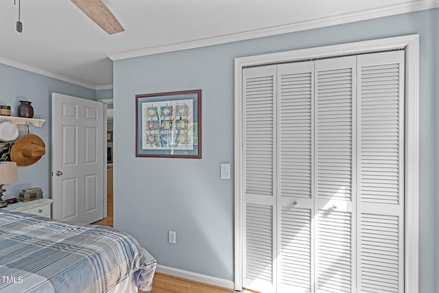 bedroom with ornamental molding, light wood-type flooring, ceiling fan, and a closet