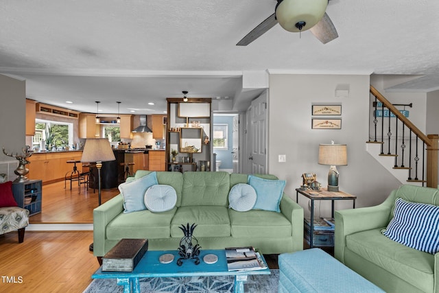 living room featuring ceiling fan, light hardwood / wood-style floors, and a textured ceiling