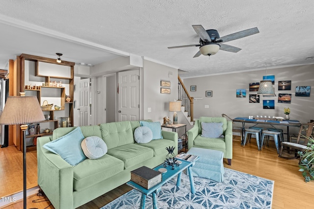 living room with light wood-type flooring, ceiling fan, and a textured ceiling