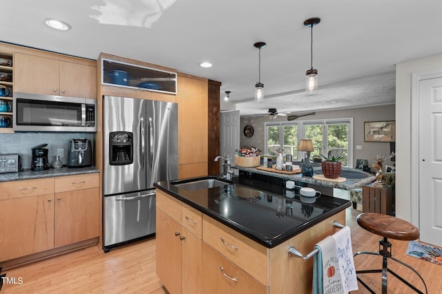 kitchen with light hardwood / wood-style flooring, stainless steel appliances, sink, and a center island with sink