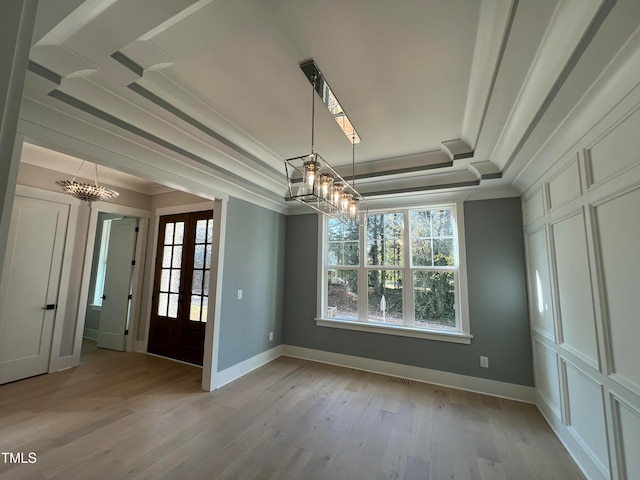 unfurnished dining area featuring french doors, a healthy amount of sunlight, crown molding, light hardwood / wood-style floors, and a tray ceiling