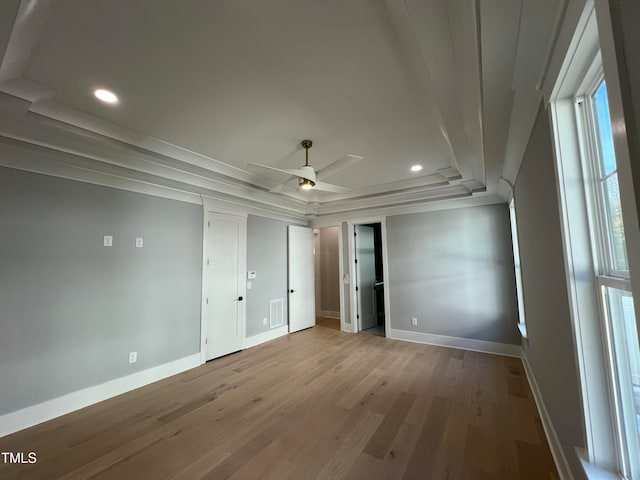 unfurnished bedroom featuring light wood-type flooring, a raised ceiling, and ceiling fan