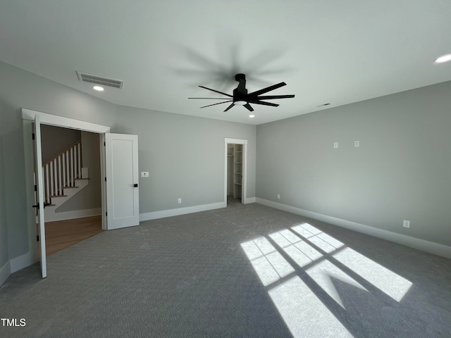 unfurnished bedroom with carpet, ceiling fan, and a walk in closet