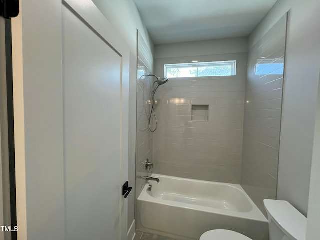 bathroom with tiled shower / bath combo and toilet