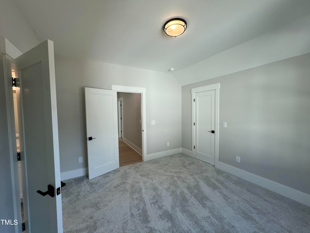 unfurnished bedroom featuring light colored carpet and lofted ceiling