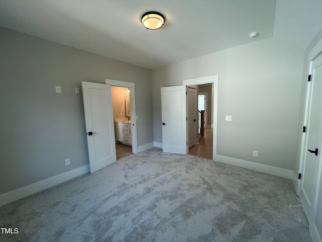 unfurnished bedroom featuring connected bathroom and light colored carpet