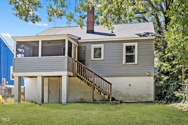 back of property featuring a sunroom and a lawn