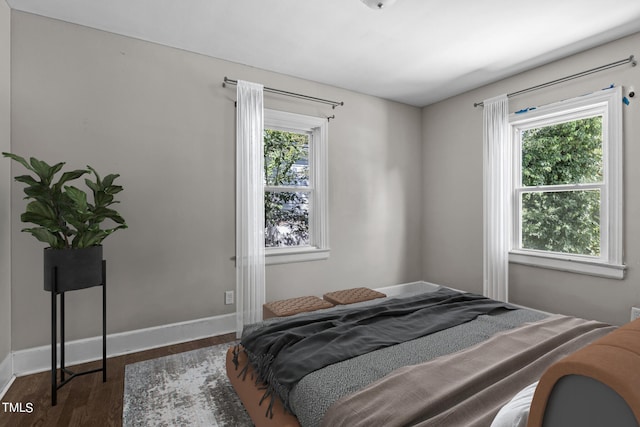 bedroom with multiple windows and dark wood-type flooring