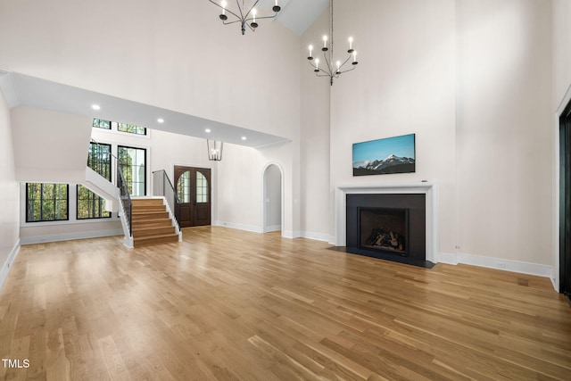 unfurnished living room featuring hardwood / wood-style floors, high vaulted ceiling, and an inviting chandelier