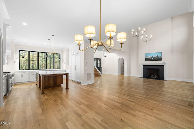 kitchen with gas range, crown molding, pendant lighting, light hardwood / wood-style flooring, and white cabinets