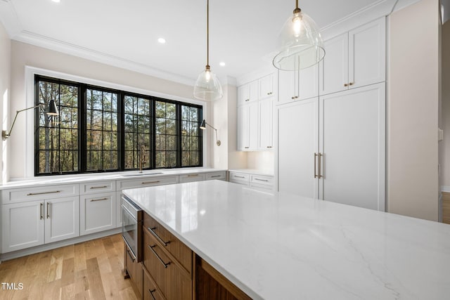 kitchen featuring light wood-type flooring, pendant lighting, built in appliances, and white cabinetry