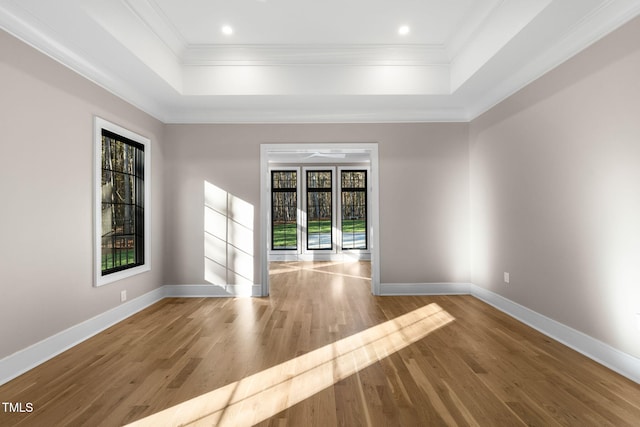 unfurnished room with light wood-type flooring, ornamental molding, and a tray ceiling