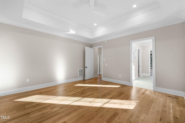 spare room featuring light hardwood / wood-style floors, ornamental molding, and a tray ceiling